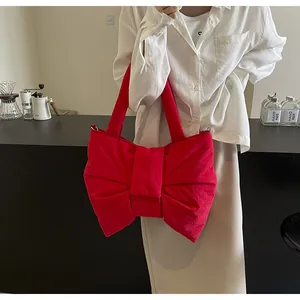 Close-up of a large red bow-shaped tote bag displayed in a stylish cafe setting