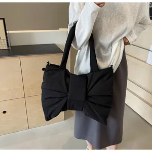 Detail of large black bow tote bag with textured fabric shown on a female model