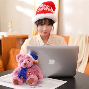 Detailed view of pink Christmas teddy bear with blue sequin hat and scarf decor