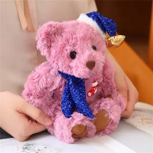 Detailed close-up of pink plush teddy bear wearing a blue glitter scarf and unicorn hat
