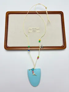 Détail du support à lunettes en cuir bleu avec breloques coquillage et perles colorées
