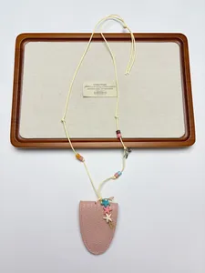 Détail de la pochette en cuir rose avec breloques d'étoiles de mer et perles pour lunettes