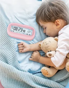 Pink digital desk alarm clock showing temperature and weather on a bedside table