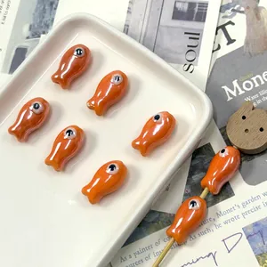 Detailed view of orange ceramic fish beads with glossy finish for DIY jewelry crafts
