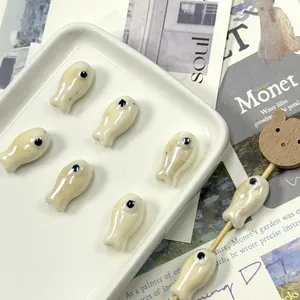 Macro view of handmade white ceramic fish beads arranged in a tray for DIY jewelry making
