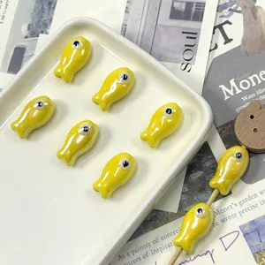 Macro detail of glossy yellow ceramic fish-shaped beads for handmade jewelry DIY crafts