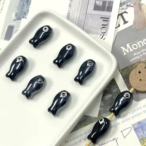Macro view of fish-shaped black ceramic loose beads for DIY jewelry making accessories