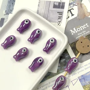 Detail of lavender purple ceramic fish beads for jewelry making displayed on a tray