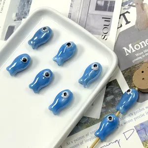 Detailed view of blue fish ceramic beads with glazed finish and large eye design on wood