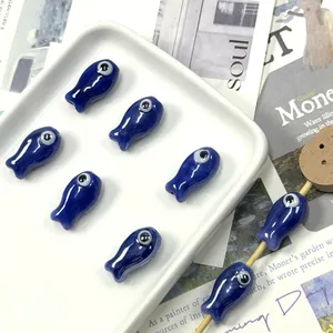 Detailed view of handmade dark blue fish-shaped ceramic beads with evil eye design
