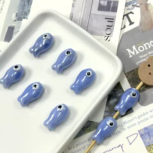 Close-up of blue fish-shaped ceramic beads with evil eye design for DIY jewelry
