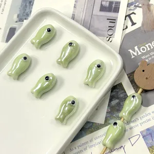 Pearlescent green fish-shaped ceramic beads for DIY jewelry making in a tray display