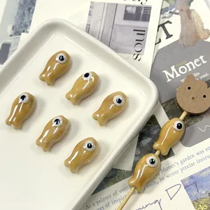 Macro detail of fish-shaped ceramic beads for DIY jewelry with glossy khaki finish