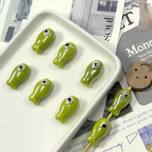 Detail of green ceramic fish beads for DIY jewelry making with a glossy finish and eyes