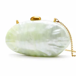 Detail of green marble acrylic shell evening bag with golden clasp and metal chain strap
