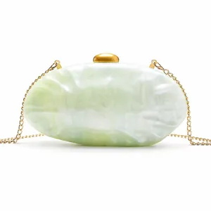Close-up of green marble acrylic shell evening bag with golden metal clasp and chain