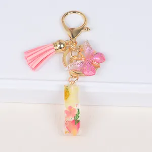 Detail of floral resin letter keychain with pink tassel and gold butterfly pendant