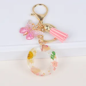 Detail of letter O keychain with dried yellow daisies, pink tassels and butterfly pendant