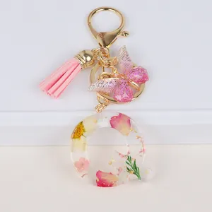 Detail of resin letter Q keychain with real dried flowers, pink tassel and butterfly