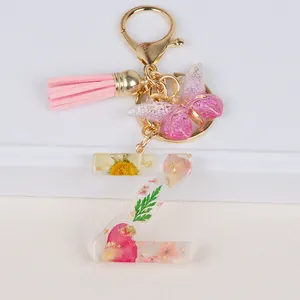 Detail of letter Z keychain with dried daisy, gold foil, pink tassel and butterfly