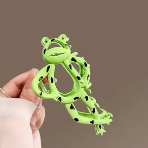 Close-up of green frog hair claw clip held in hand showing scale and matte finish
