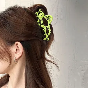 Detail of cute green frog hair claw clip holding long hair on back of head