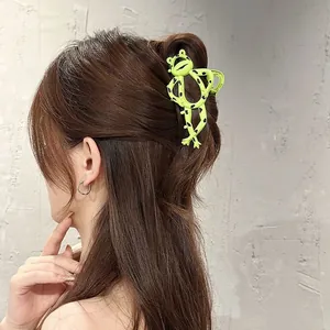 Macro detail of the creative neon green frog-shaped hair claw clip on a model's hair