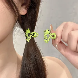 Detail view of a mini green cartoon frog hair claw clip styled on a model hair strand
