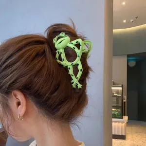 Detail of creative green frog hair claw clip holding thick hair in a stylish updo