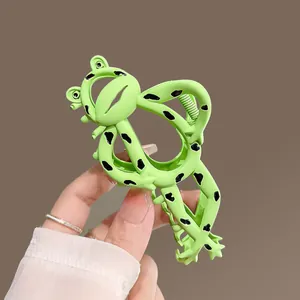 Creative green frog hair claw clip with black spots for thick hair, shown held in hand