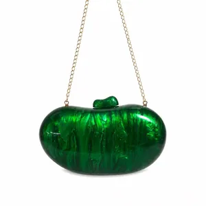 Macro shot of green marble acrylic clutch bag with golden chain and pebble texture