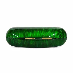 Detail view of emerald marble acrylic evening bag with capsule shape and gold metal hinges