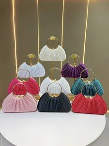 Détail de pochettes de soirée montrant le tissu en soie plissée et les anneaux dorés