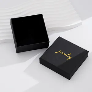 Detail of a square black jewelry gift box with textured finish and gold lettering