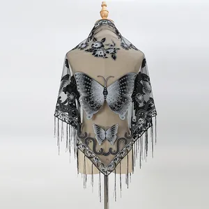 Detail of delicate lace shawl featuring butterfly embroidery and long black tassels