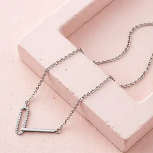 Minimalist silver geometric necklace with zircon pendant on pink display stand