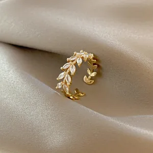 Elegant adjustable olive leaf ring with cubic zirconia on champagne silk background