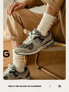 Detail of retro gray suede sneakers worn with thick white cotton crew socks and khaki pants