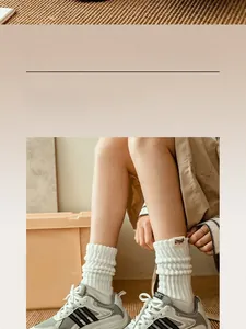 Close-up of white ribbed crew socks with Happy Time woven label and retro mesh sneakers