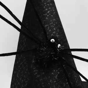 Close-up of black plush spider detail with white eyes on a textured witch hat