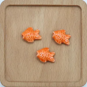 Tre perle di ceramica a forma di pesce arancione per gioielli fai-da-te su legno