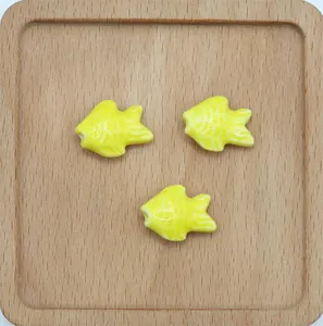 Tre perle a forma di pesce in ceramica gialla con smalto lucido per creazione di gioielli