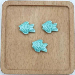 Dettaglio di tre perline in ceramica azzurra a forma di pesce per creazione di gioielli