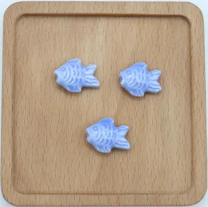 Dettaglio macro di tre perle di pesce in ceramica blu chiaro con scaglie per fai-da-te