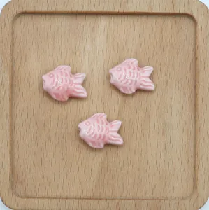 Tre perle di ceramica rosa a forma di pesce con smalto lucido per creazione di gioielli