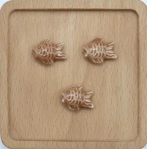 Dettaglio macro di tre perle in ceramica a forma di pesce marrone con strisce bianche
