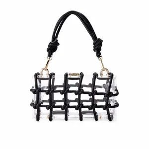 Detail of transparent acrylic handbag with black braided mesh and gold clasp closure