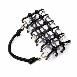 Detailed side view of clear acrylic handbag with black braided mesh and gold hardware