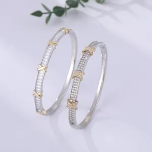 Close-up of two-tone crossover bangles with sparkling crystals and silver gold finish