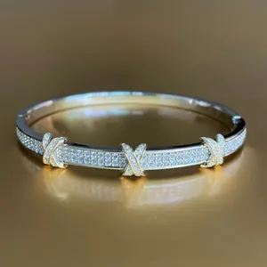 Macro detail of dual-tone crisscross bangle with pavé zircons and gold X motifs